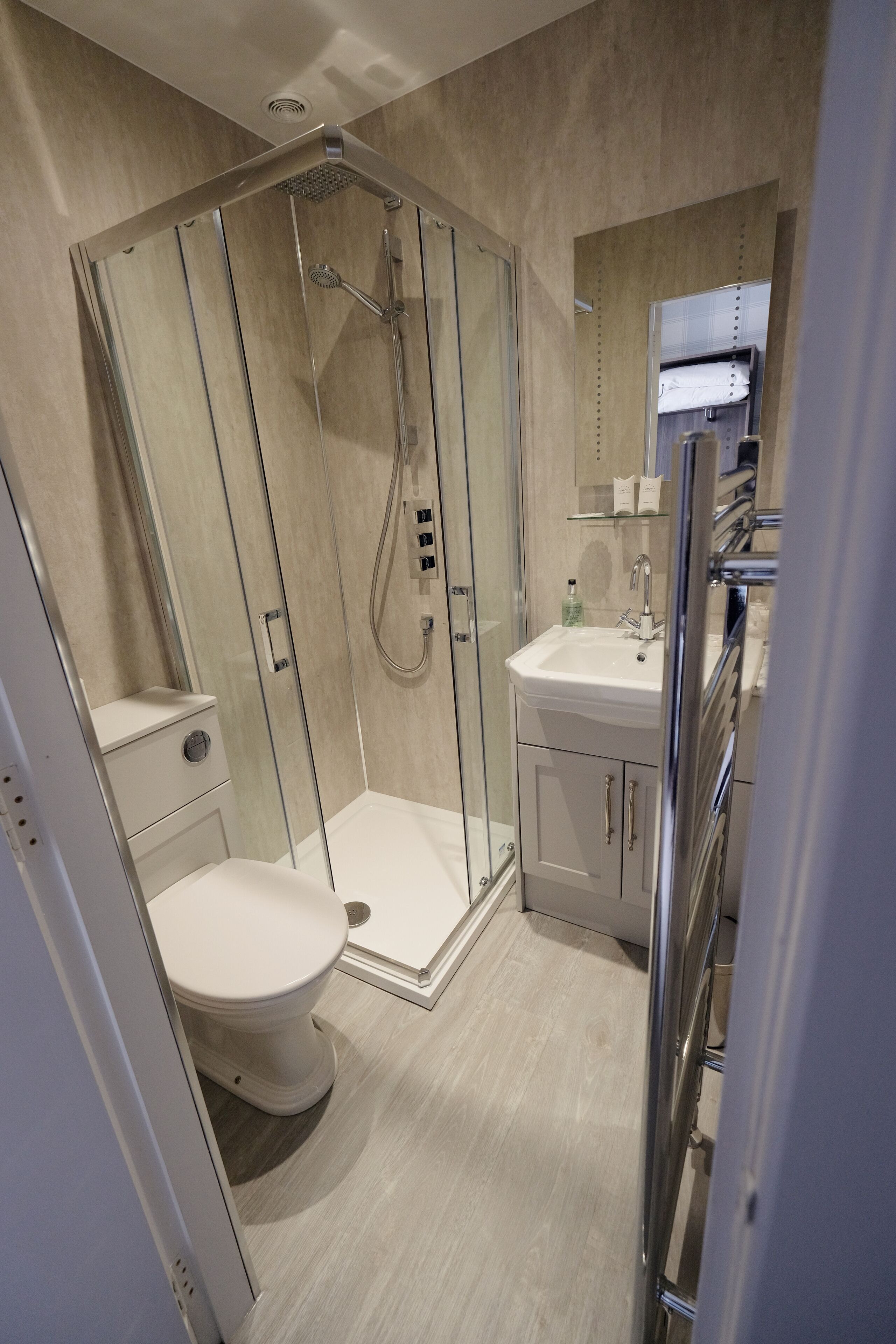 Un baño moderno con ducha de vidrio, inodoro blanco y lavamanos con espejo.