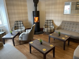 A cozy room with plaid furniture, a central wood-burning stove, and a mirror on the wall.