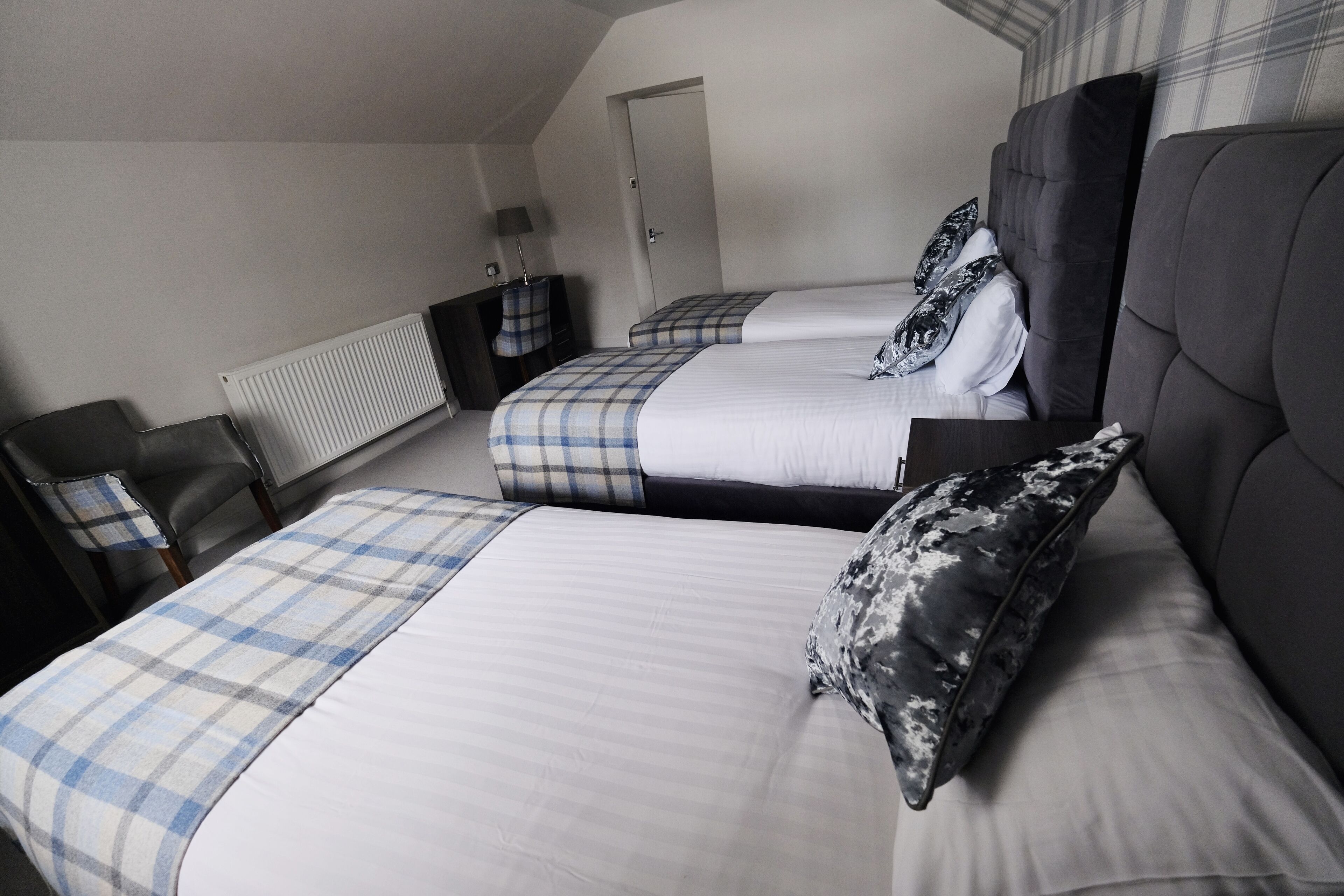 A hotel room with two beds, a radiator, a desk, and a chair.