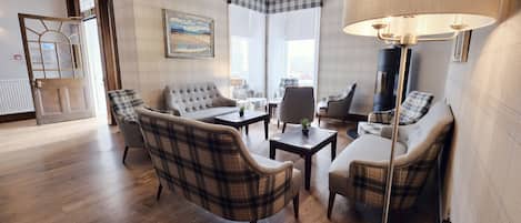Una sala de estar con sillones a cuadros, un sofá, una mesa de centro y una lámpara de pie.