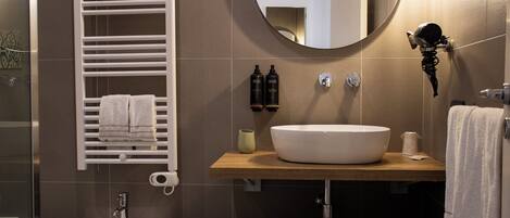 A modern bathroom with a white sink, a towel rack, a mirror, and a bidet.