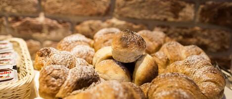 A variety of pastries and bread displayed on a table with a brick wall background.