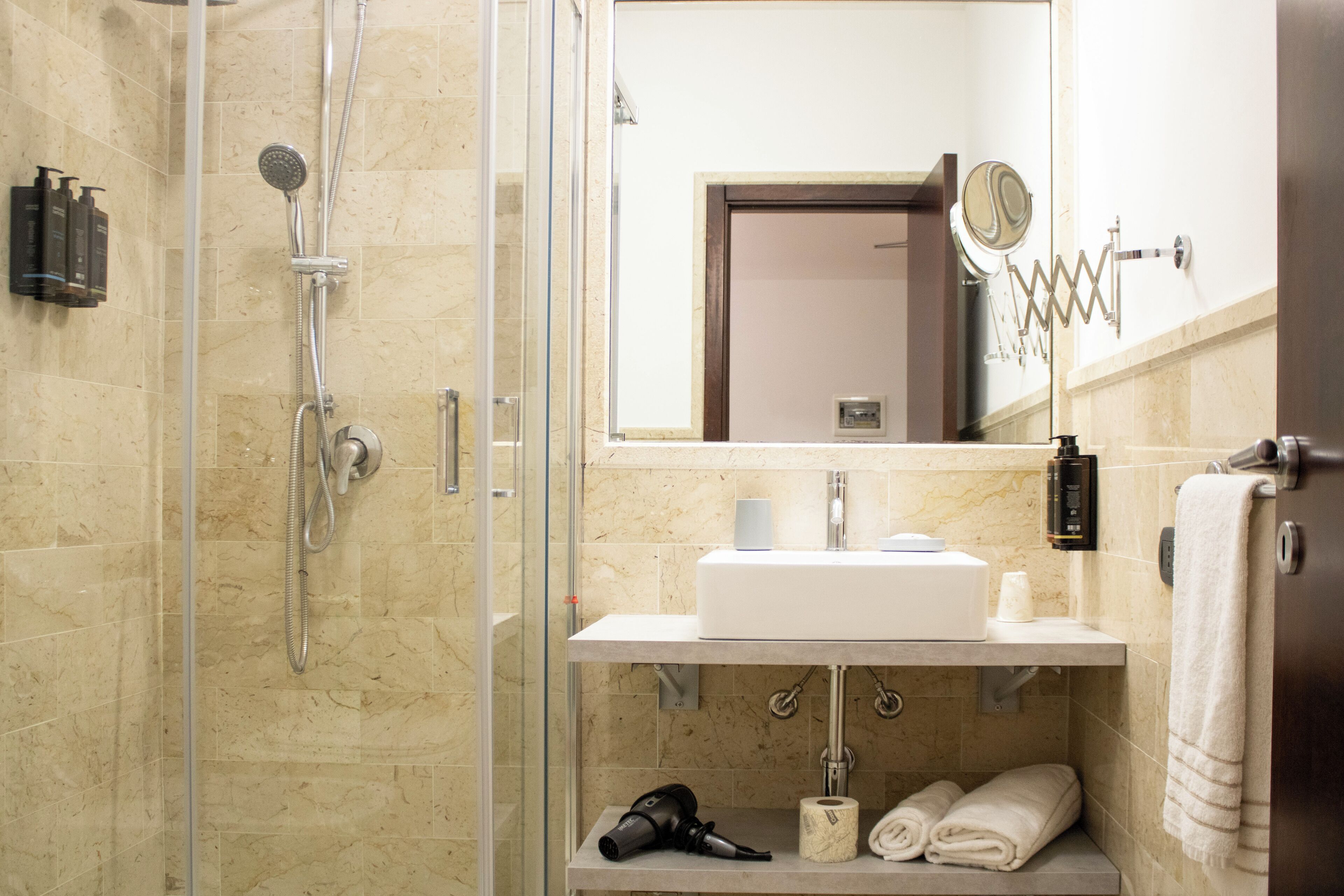 A modern bathroom with a glass-enclosed shower, a sink with a mirror above, and a towel rack.