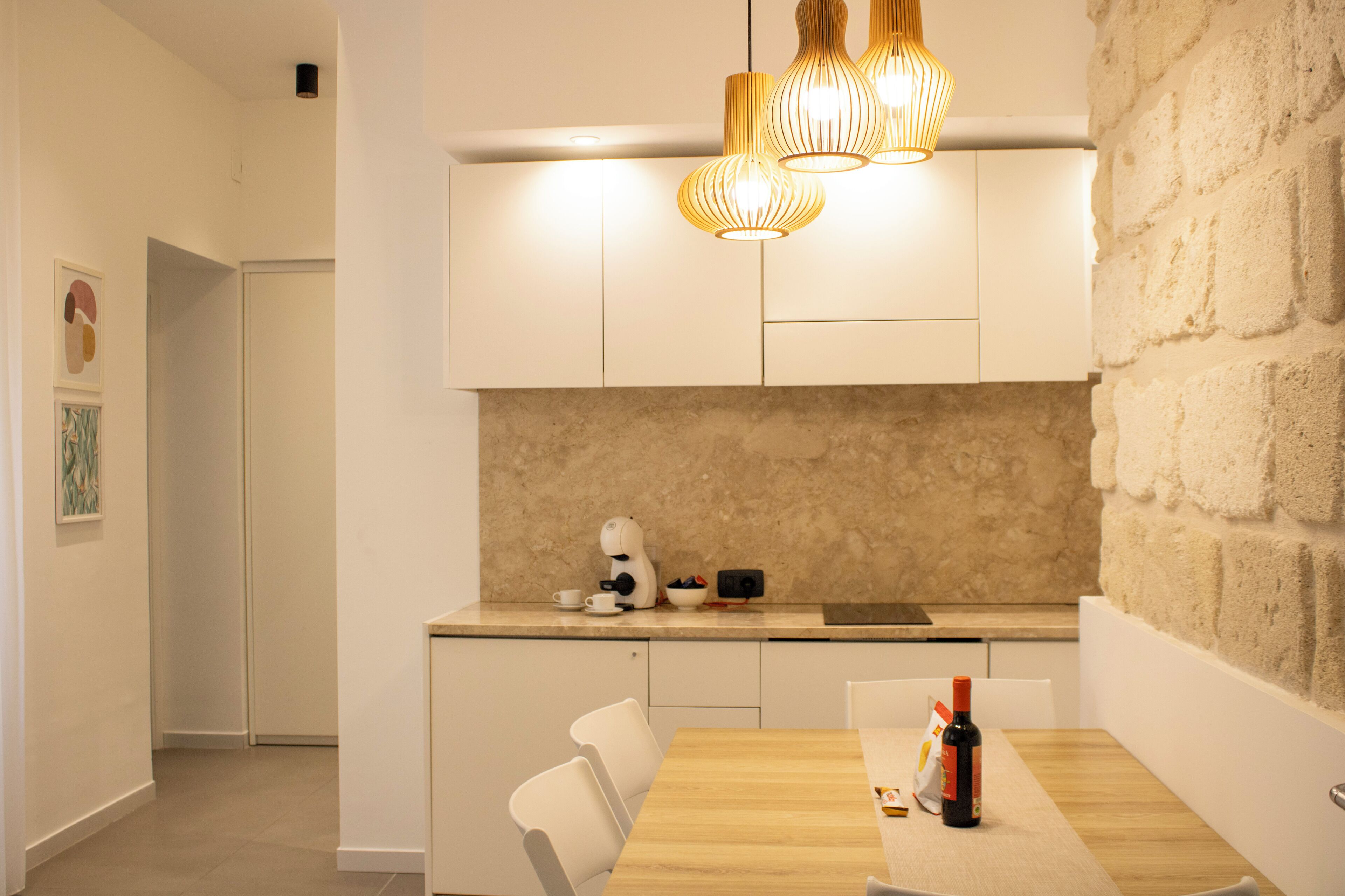 Eine moderne Küche mit weißen Schränken, einer Marmor-Spritzschutzwand und einem Holztisch.