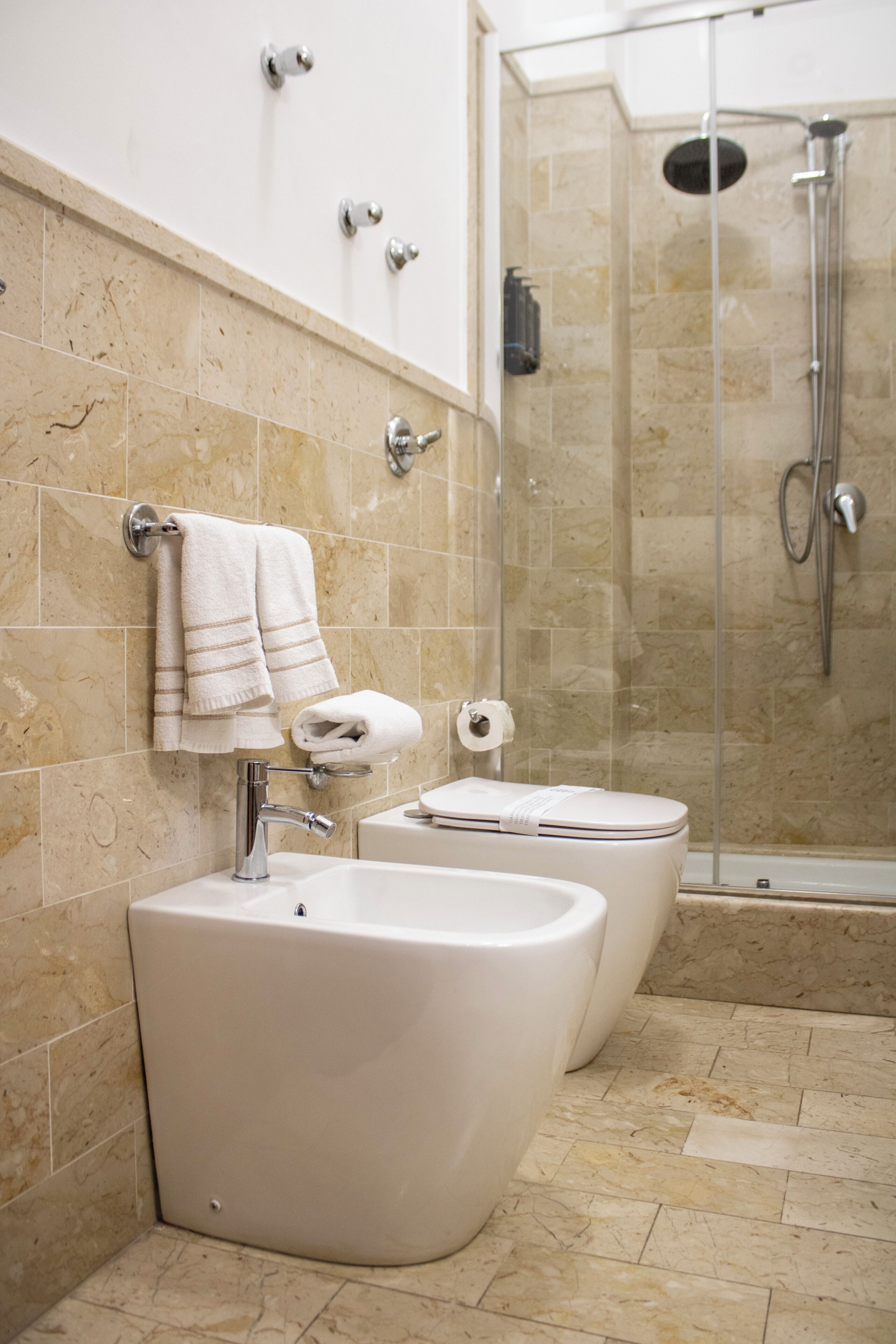 Un baño con dos lavabos, un inodoro y una ducha con mampara de vidrio.