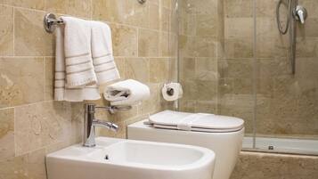 Un baño con dos lavabos, un inodoro y una ducha con mampara de vidrio.