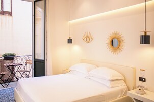 Una camera d'albergo con un letto, un comodino, uno specchio e un piccolo tavolo con sedie.