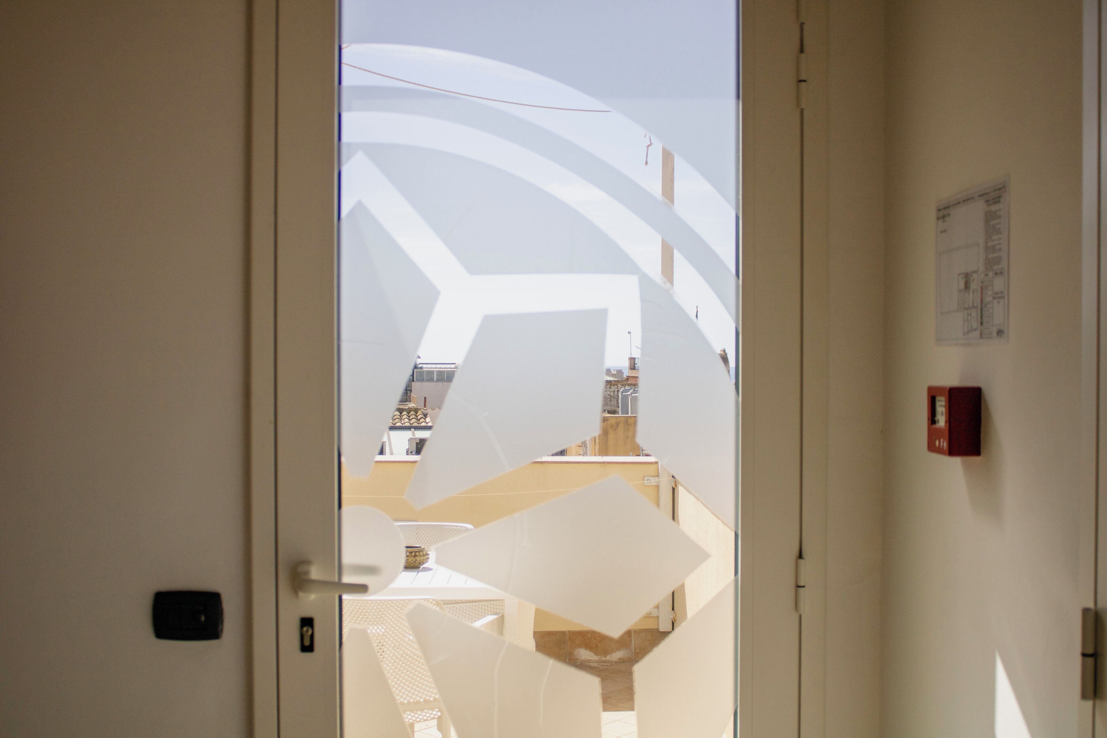 A door with a geometric pattern and a fire alarm on the wall.