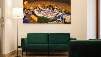 A living room with a green sofa, a floor lamp, and a painting on the wall.