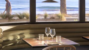 Comedor con vistas a la playa, que incluye una mesa con vasos y un banco.