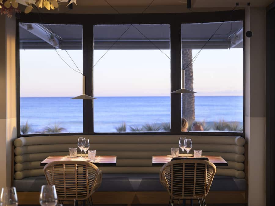 Comedor con vista al océano, con asientos acolchados y mesas.