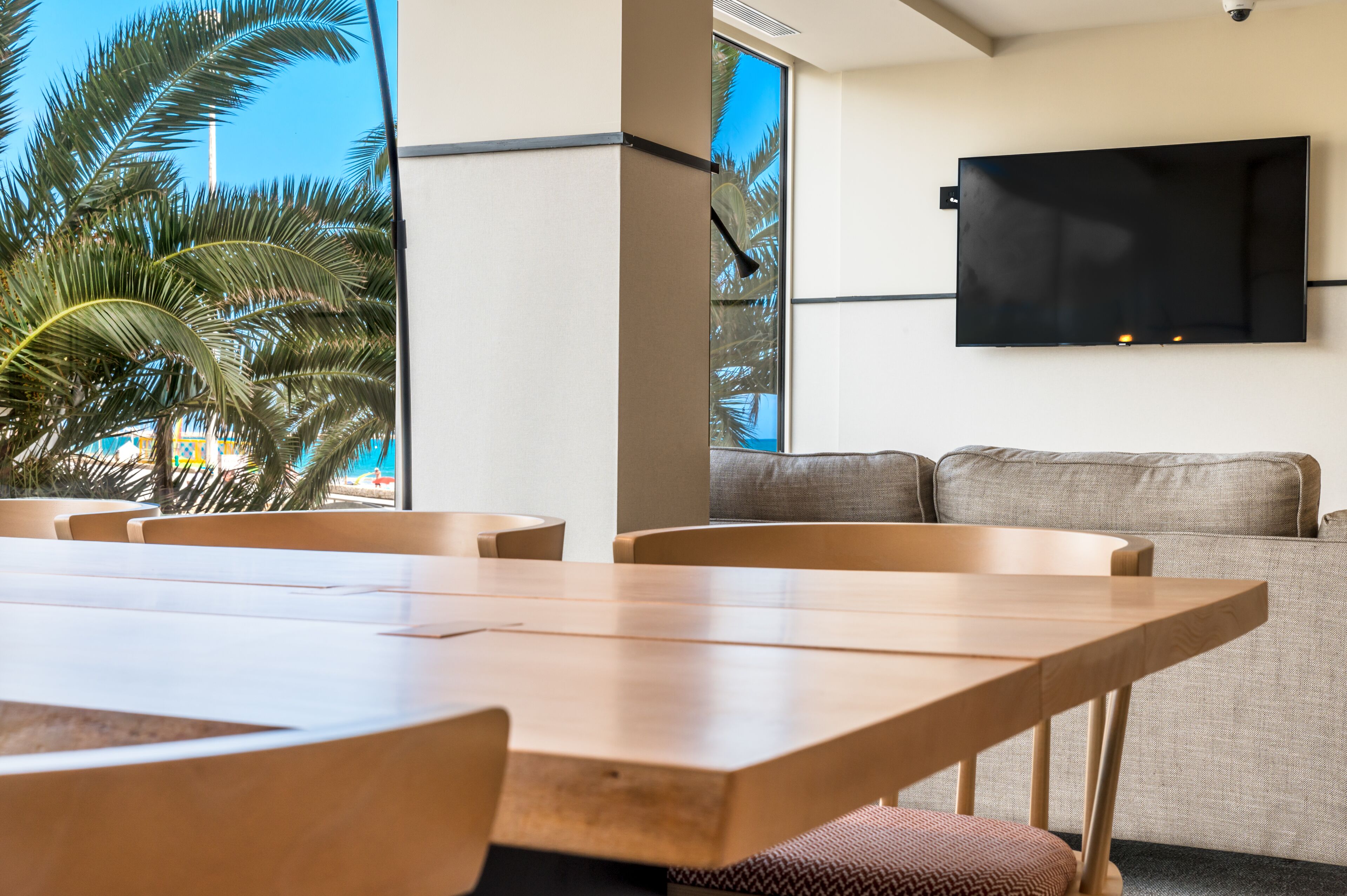 Una habitación moderna con un televisor de pantalla plana grande montado en la pared, un sofá y una mesa de comedor con sillas.