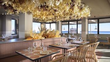 Un restaurante con mesas dispuestas para comer, un techo decorativo y grandes ventanales que ofrecen vistas.