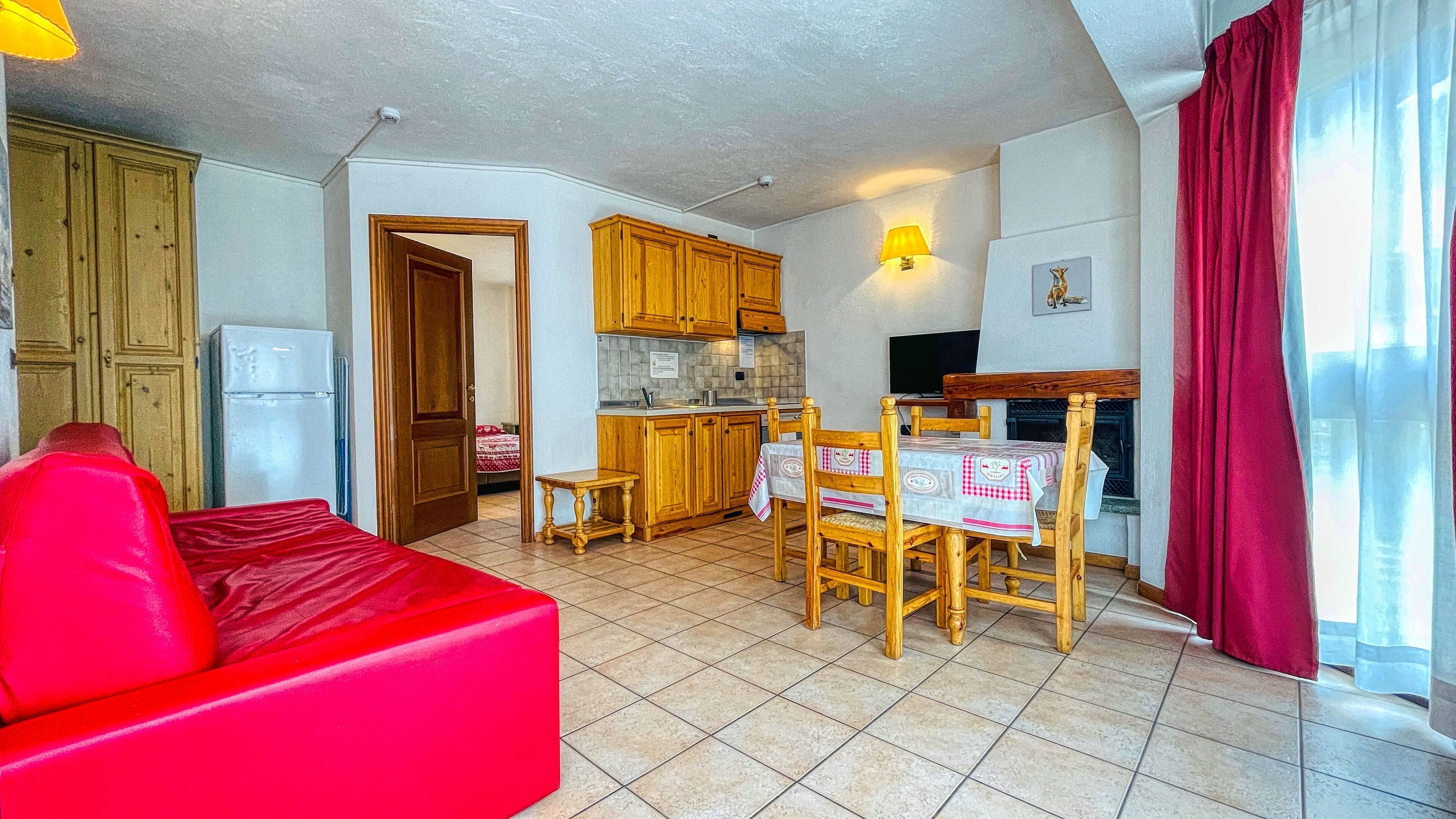 A compact living space with a kitchen, dining area, and a red sofa.