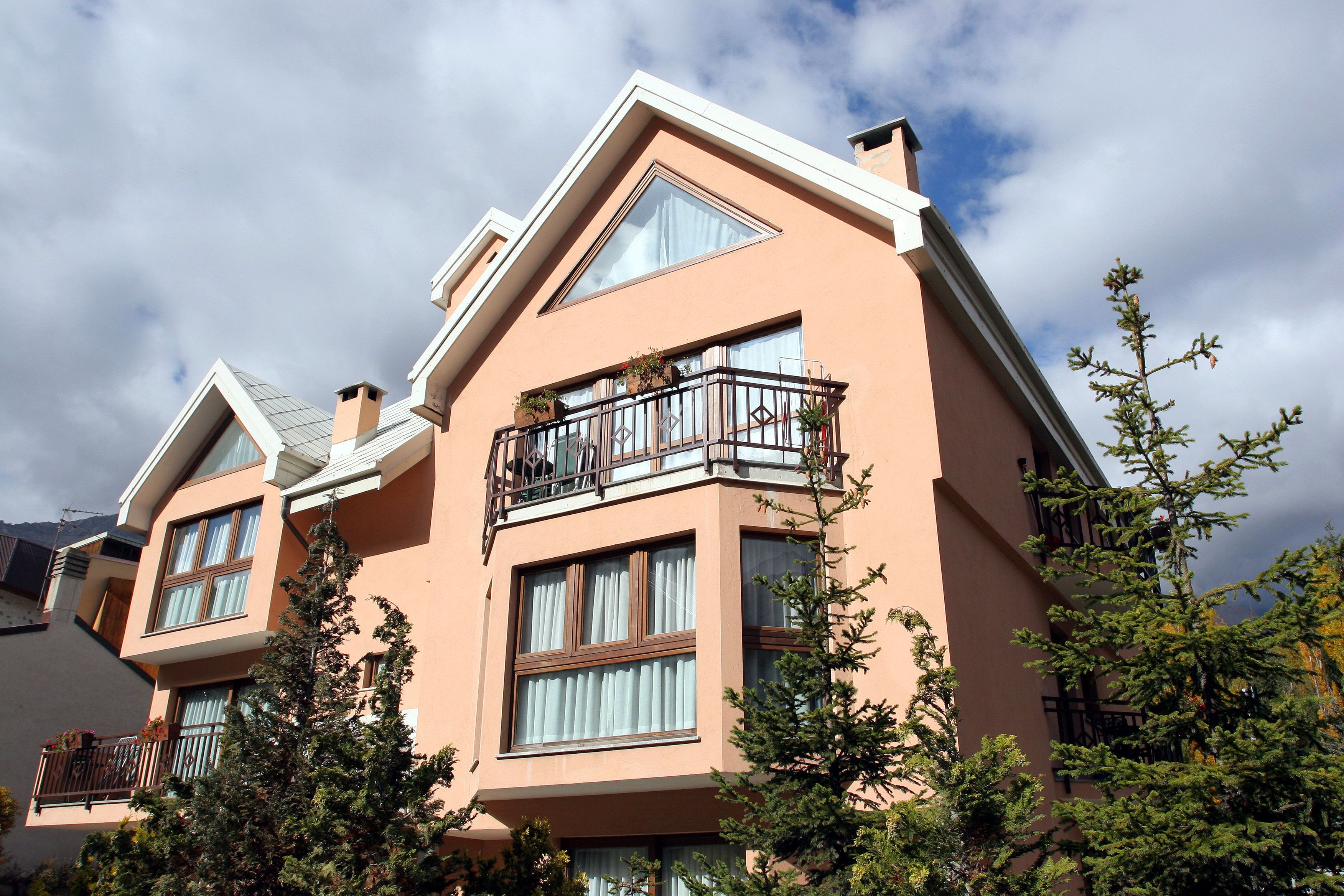 A multi-story building with balconies, large windows, and a clear sky.