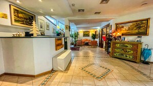 A hotel lobby with a reception desk, a sofa, and a patterned floor. - Residence villa Frejus (Bardonecchia)
