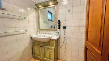 Ein Badezimmer mit Waschbecken, Spiegel, Handtuchhalter und einem Fön.