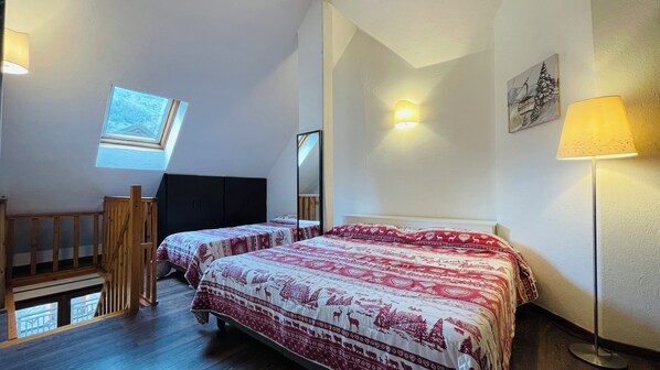 A bedroom with two beds, a skylight, a mirror, and a lamp. - Residence villa Frejus (Bardonecchia)