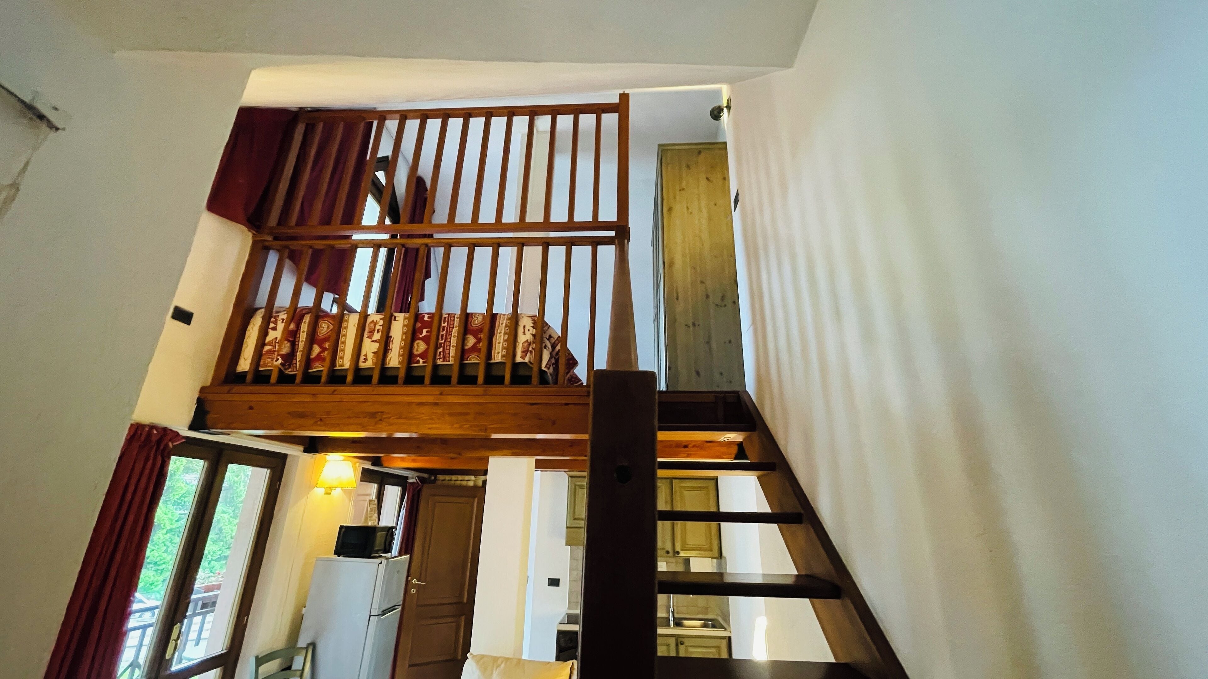 A staircase with a wooden railing leading to a second-floor bedroom.