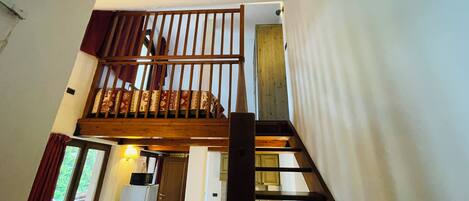A staircase with a wooden railing leading to a second-floor bedroom.