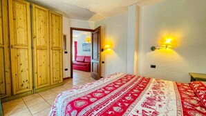 A bedroom with a large bed, wooden wardrobe, and two wall-mounted lamps. - Residence villa Frejus (Bardonecchia)