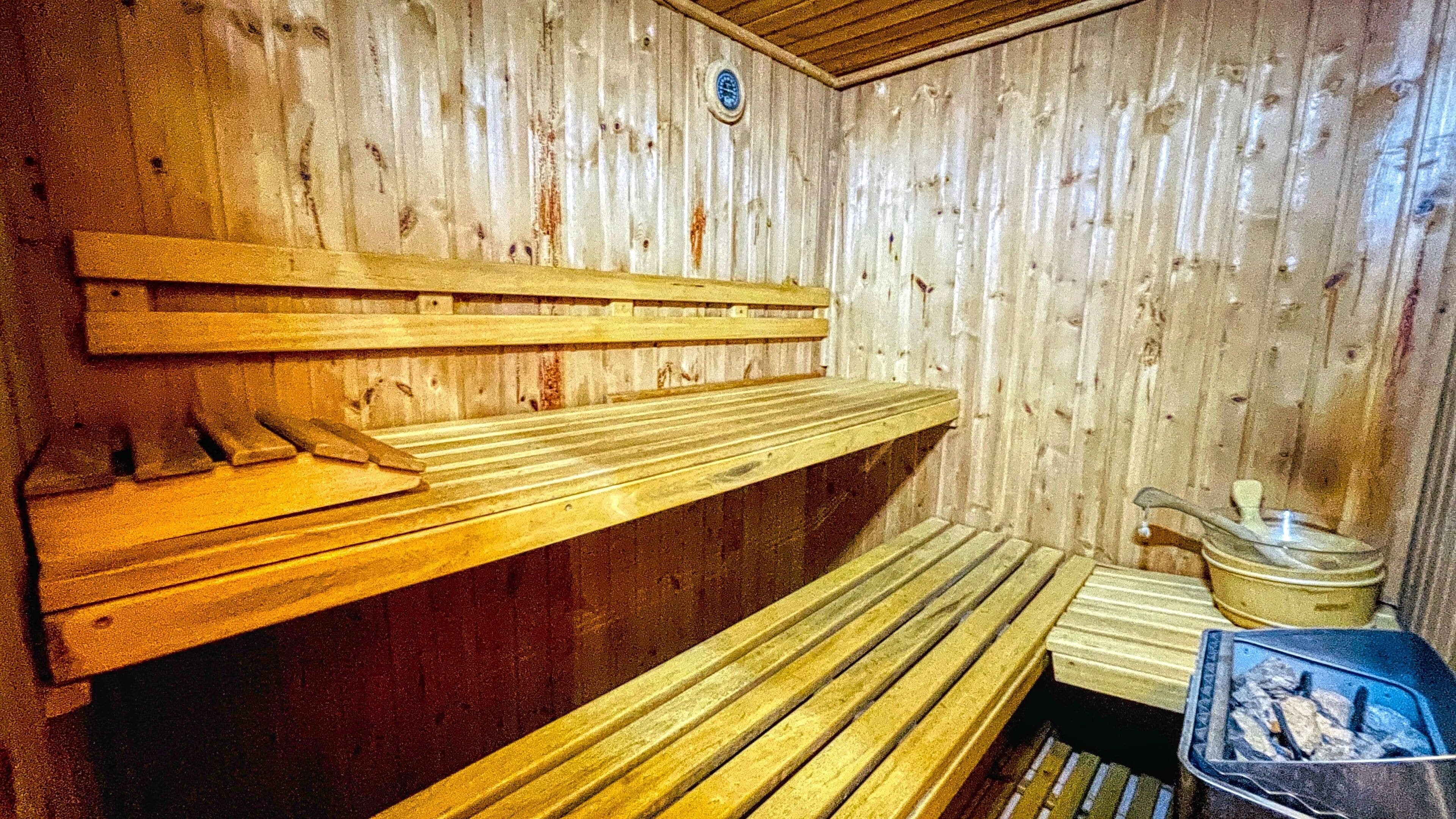 A sauna with wooden benches and a small table with a container.