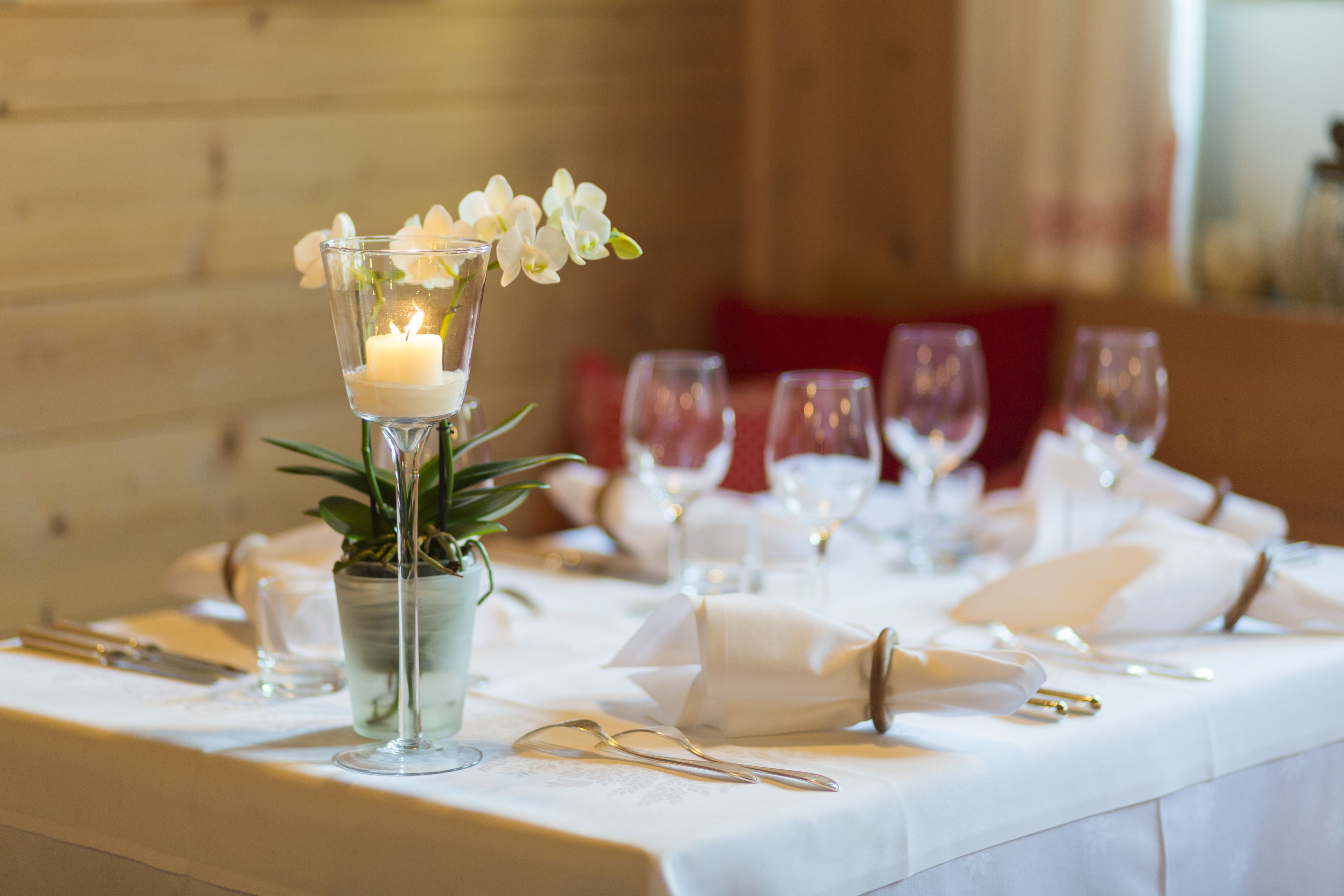 A dining table set with white tablecloth, candles, and glassware.