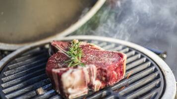 Een steak op een grill met duidelijke grillstrepen en een takje rozemarijn erbovenop.