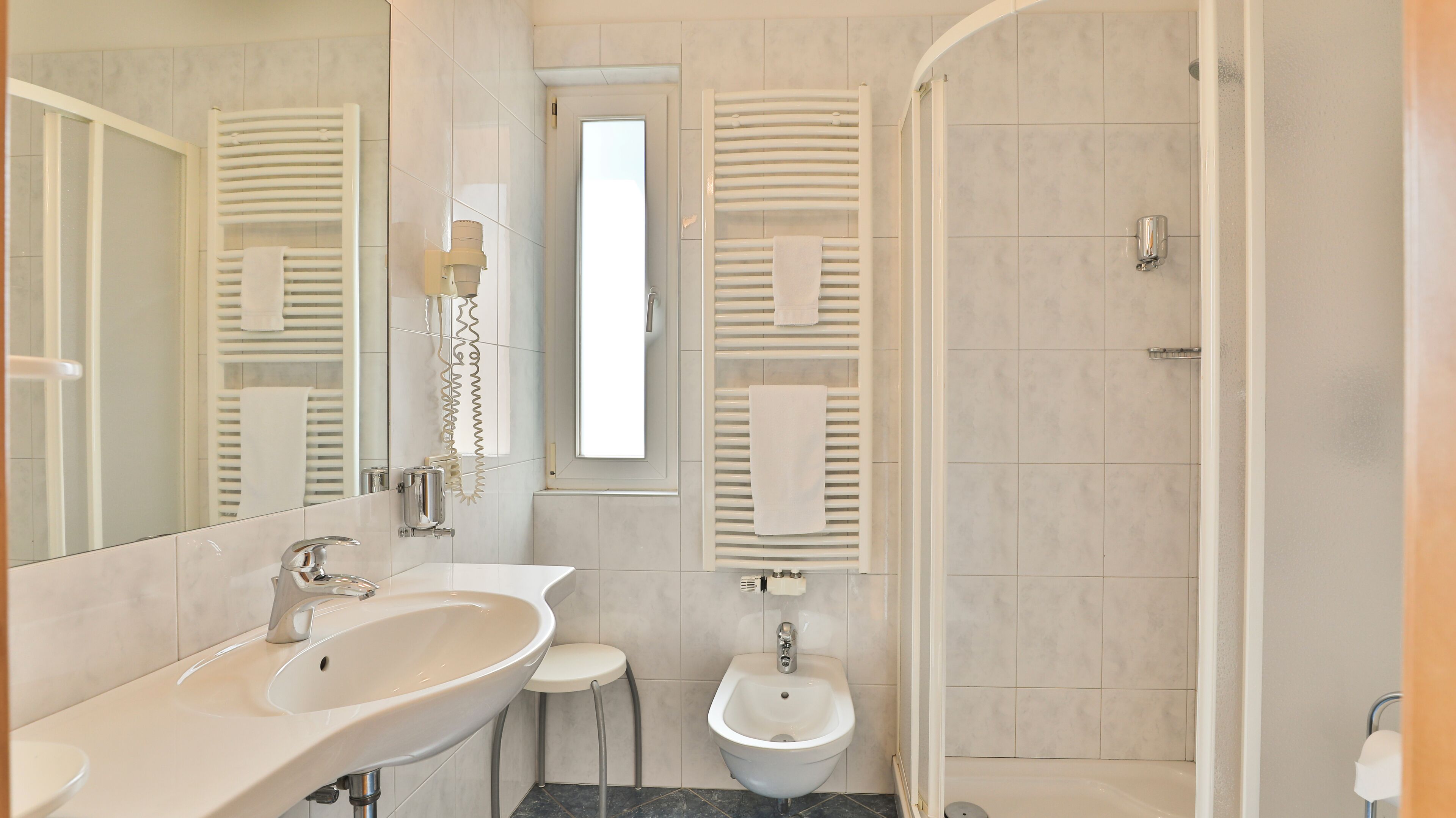 A modern bathroom with a sink, bidet, and shower.
