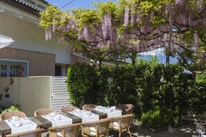 An outdoor dining area with wicker tables and chairs, covered by a white tablecloth. - Hotel Sparerhof (Terlano)