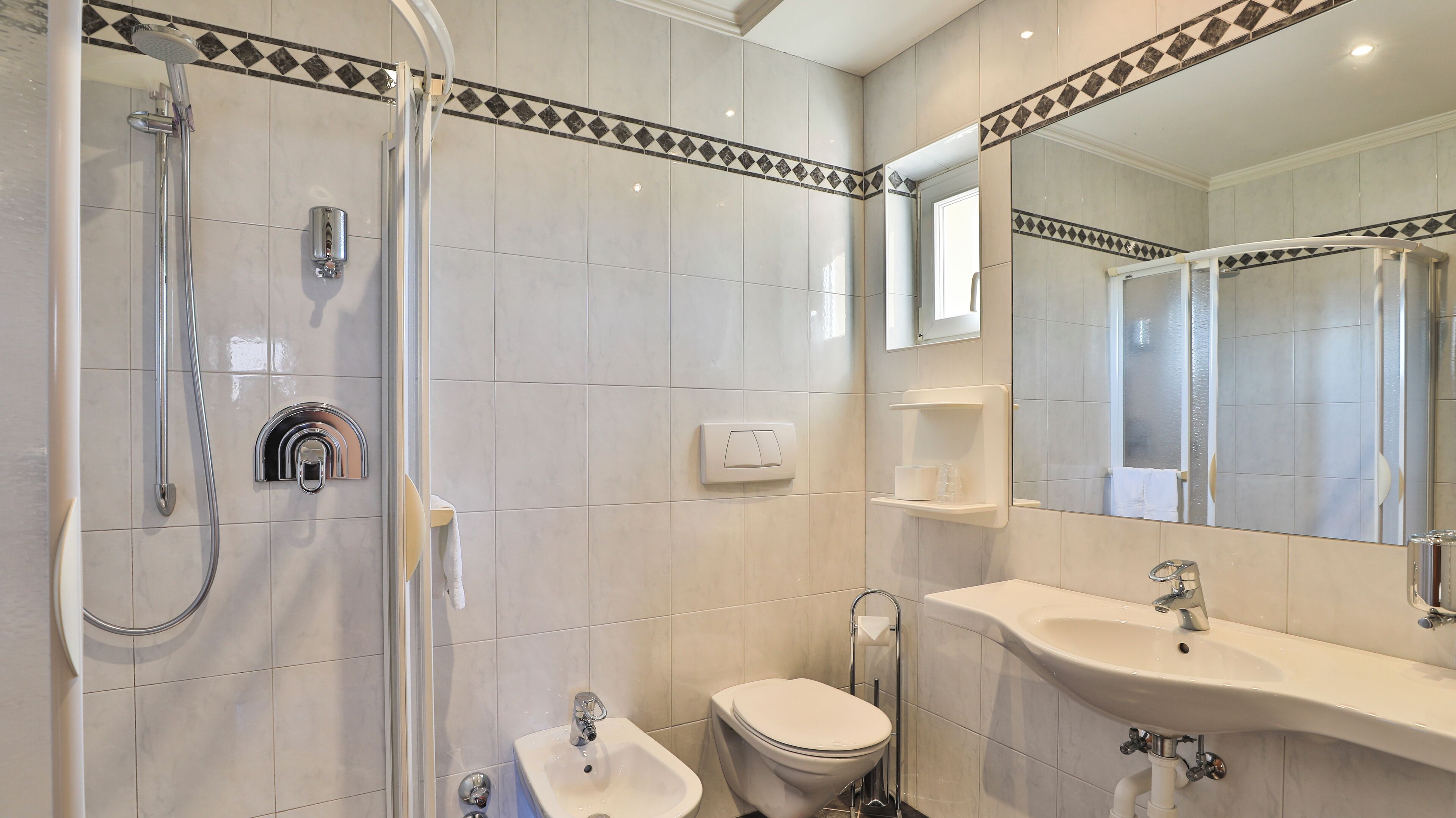 Une salle de bain moderne équipée d’une douche, de toilettes, d’un lavabo et d’un grand miroir.