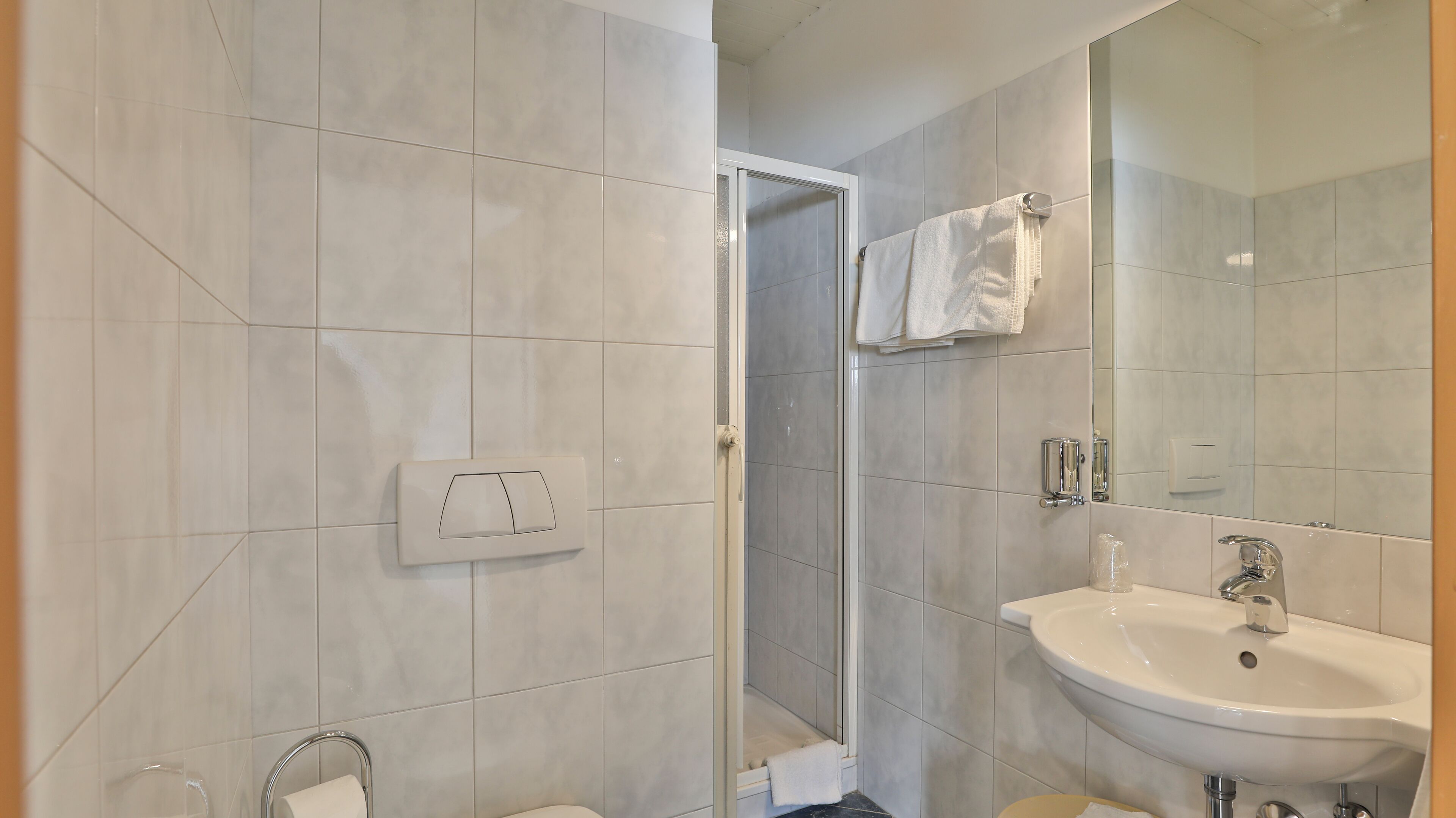 Een moderne badkamer met een douche, een wastafel en een spiegel.