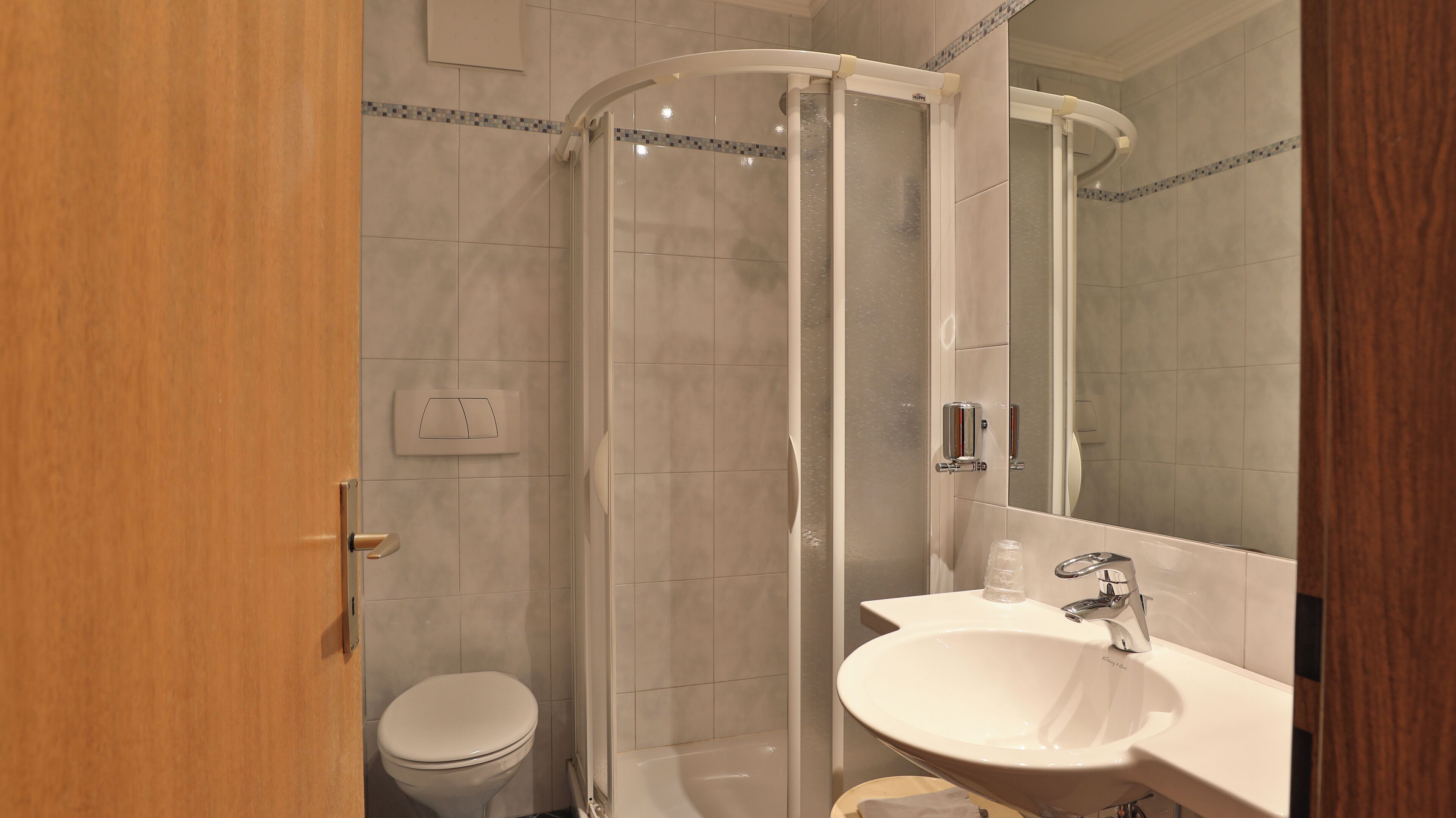 Une salle de bain comprenant des toilettes, un espace douche et un lavabo avec un miroir.