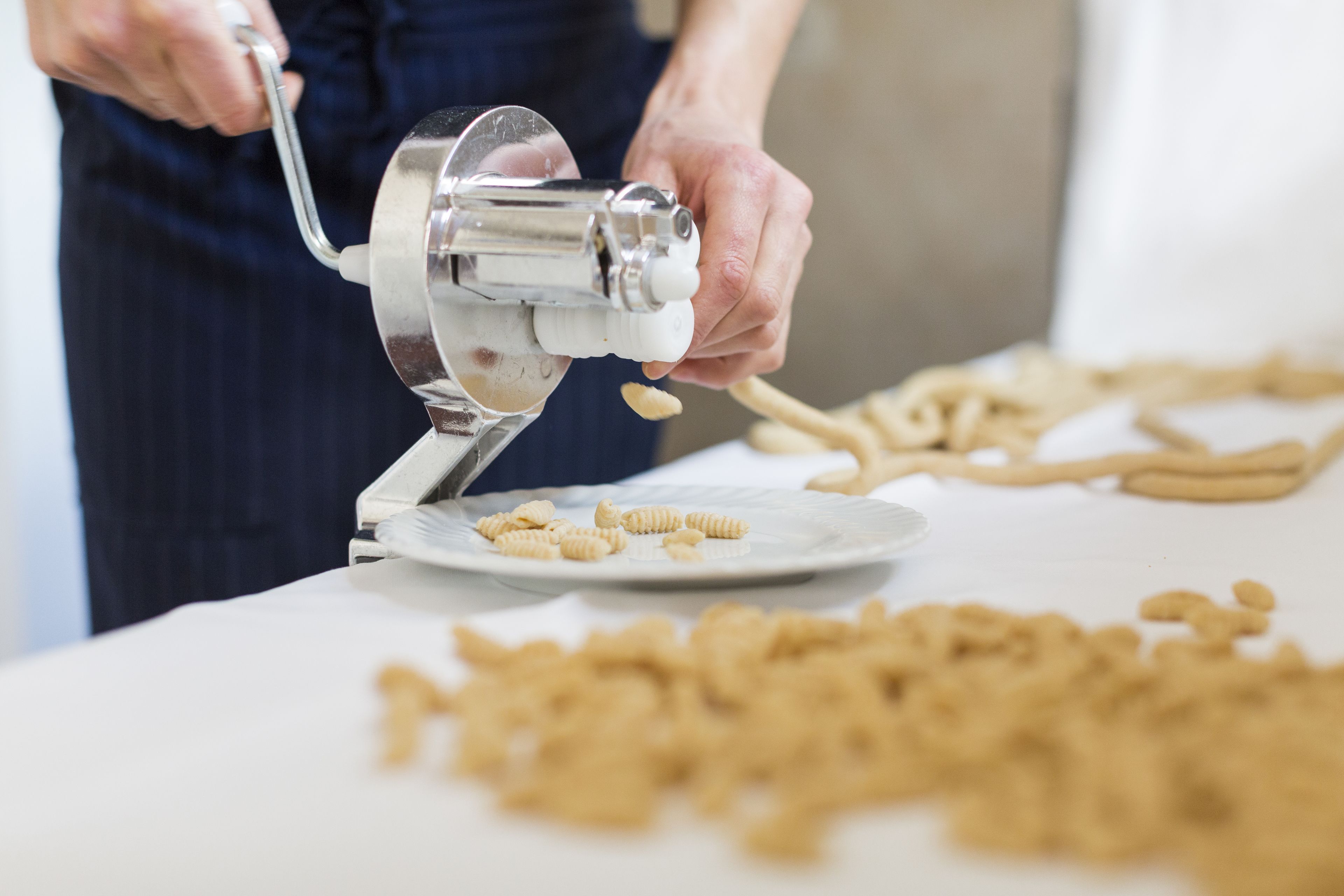 Une personne utilise une machine à pâtes pour façonner la pâte à pâtes.