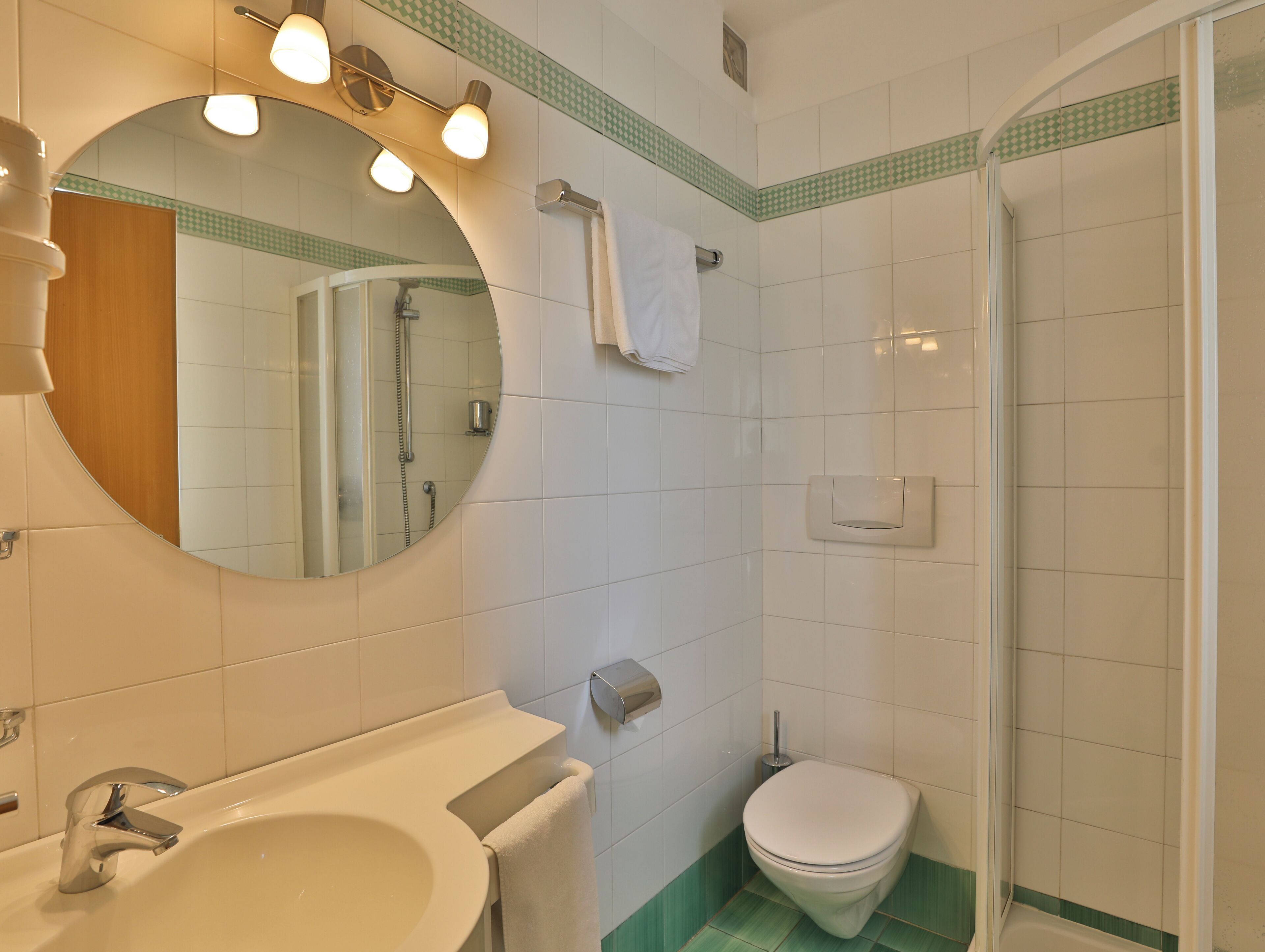 A bathroom with a sink, mirror, toilet, and shower.