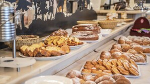 Un bufé con diversas opciones de panadería, incluyendo pasteles, bollería y pan.