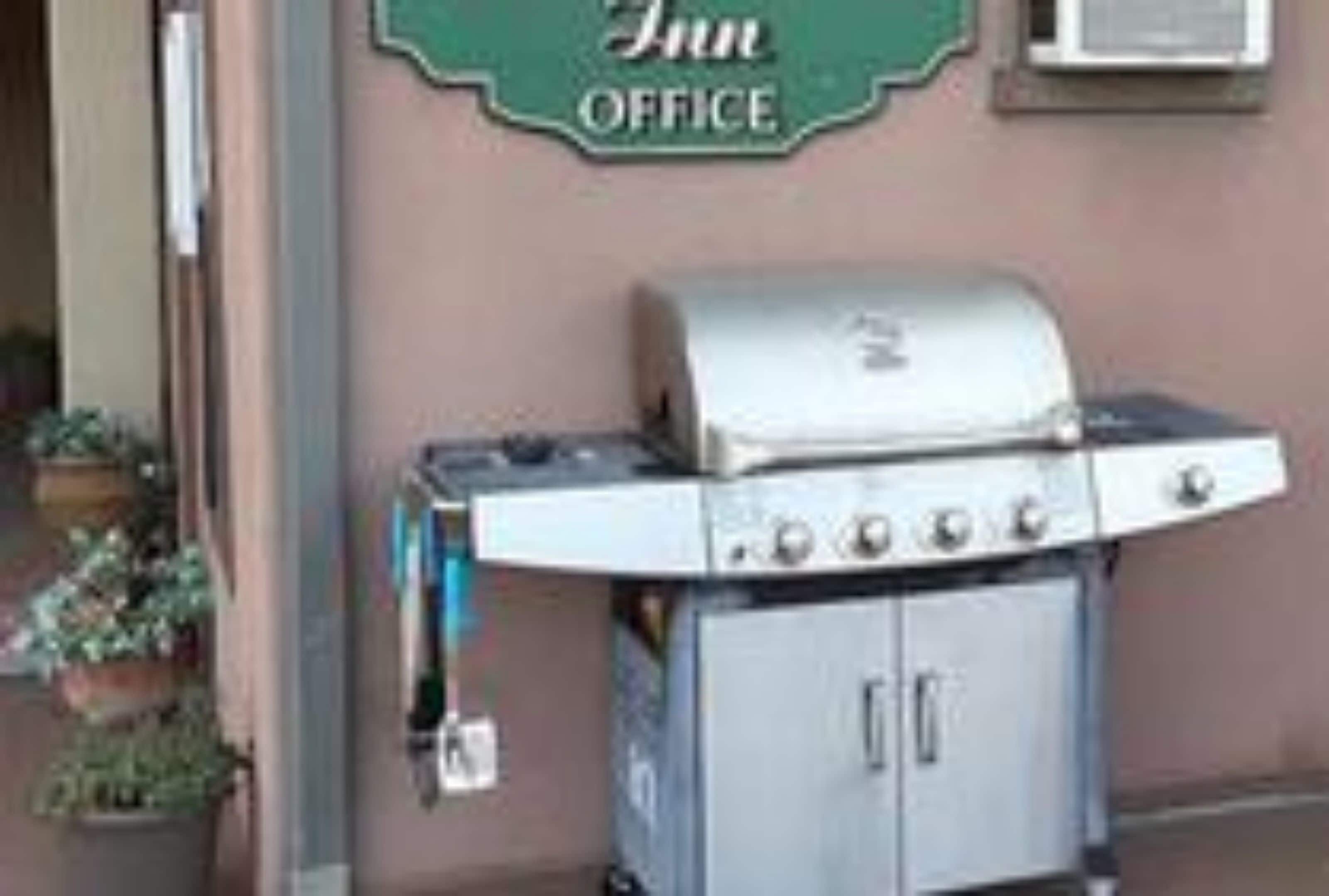 A grill and a refrigerator outside a building with a sign that reads "Inn Office".
