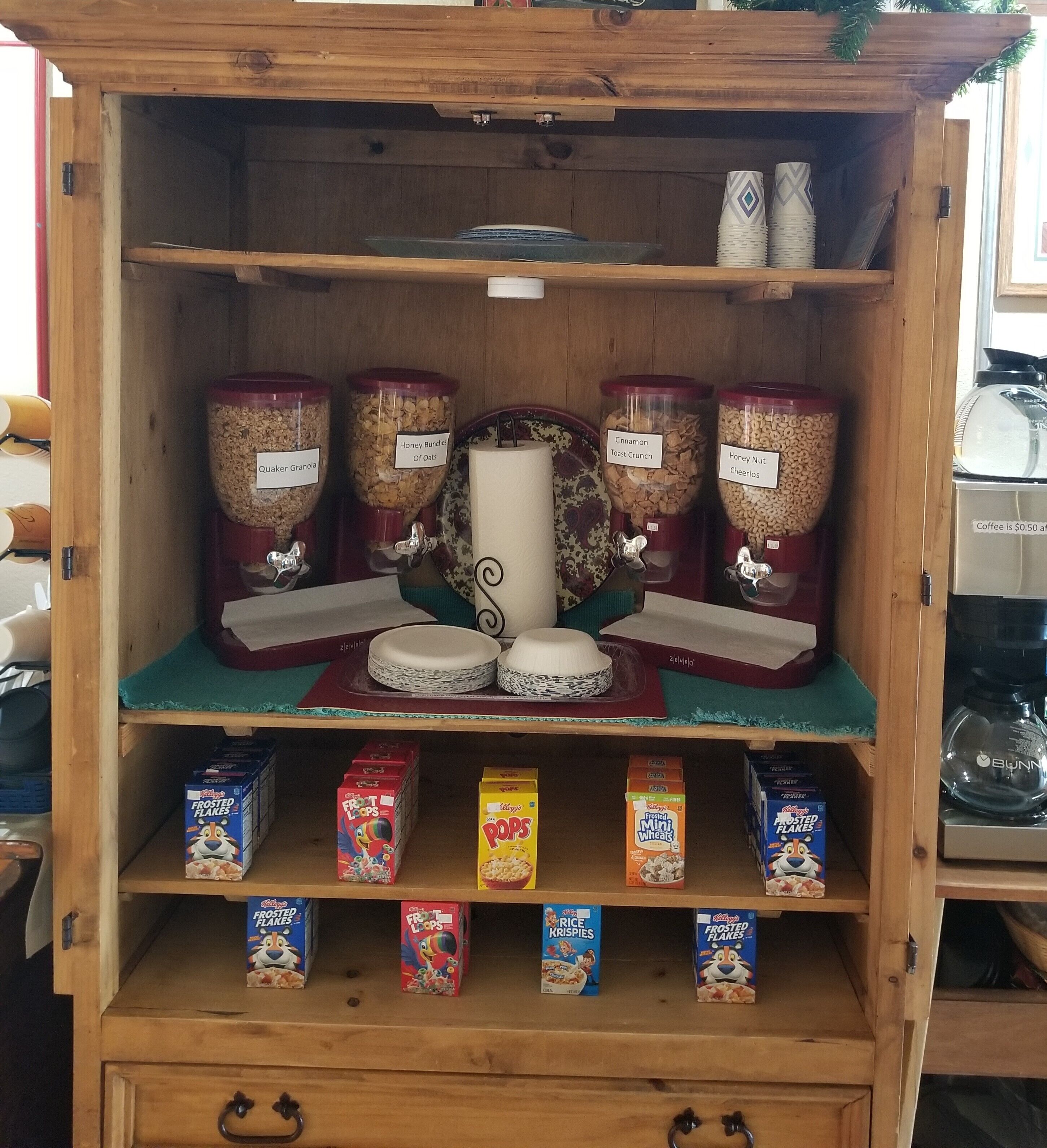 Un meuble en bois contenant des récipients étiquetés remplis de granola, de flocons d’avoine et de céréales.