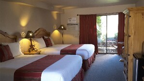 Et hotelværelse med to senge, et træskab, et skrivebord og et vindue med røde gardiner.