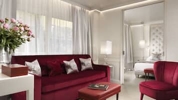 Une chambre d’hôtel moderne avec un canapé rouge, un fauteuil assorti, une petite table et une table de chevet avec une lampe.