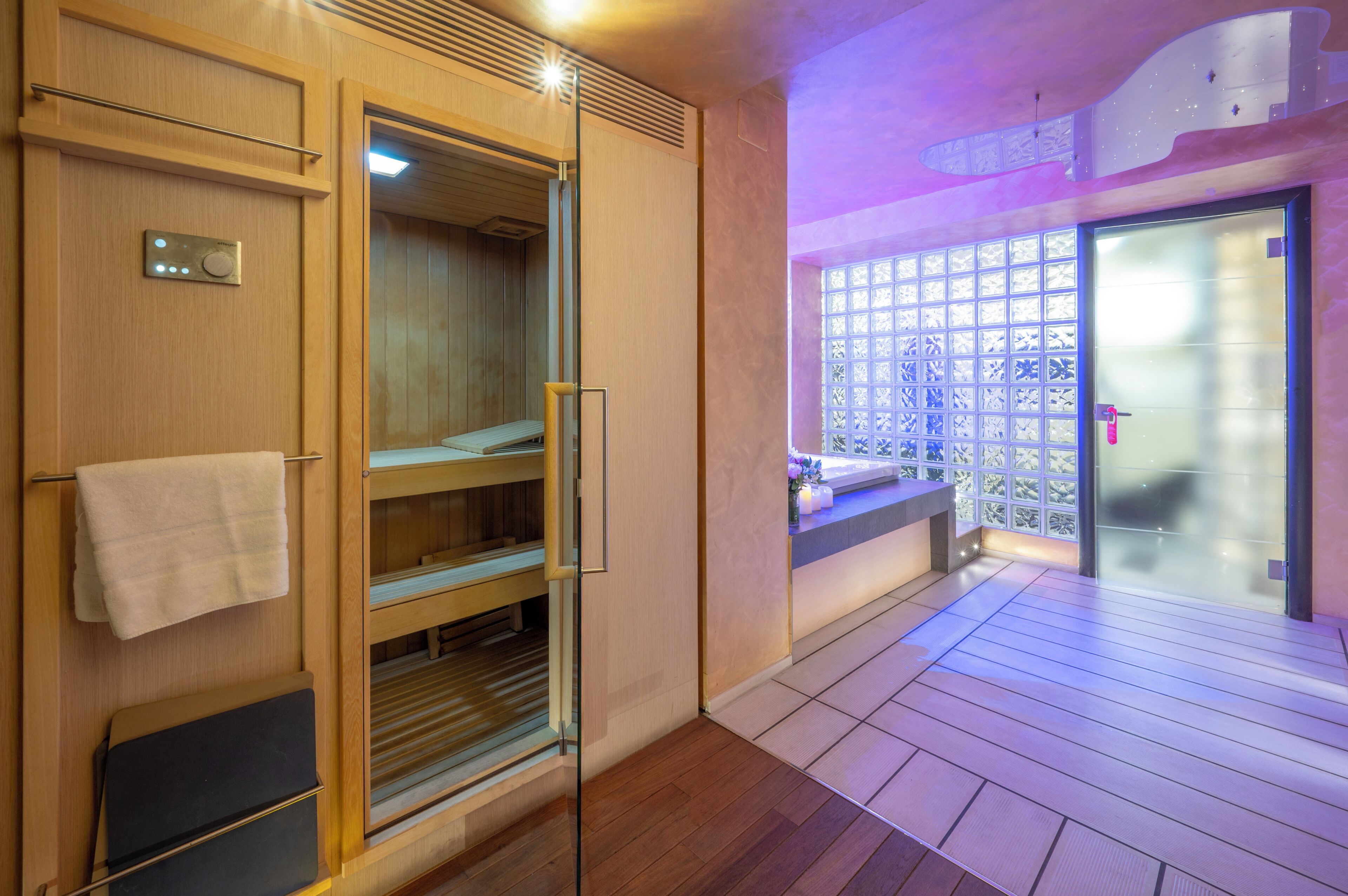 Una sala de sauna con paredes de madera, una puerta de cristal y un banco.