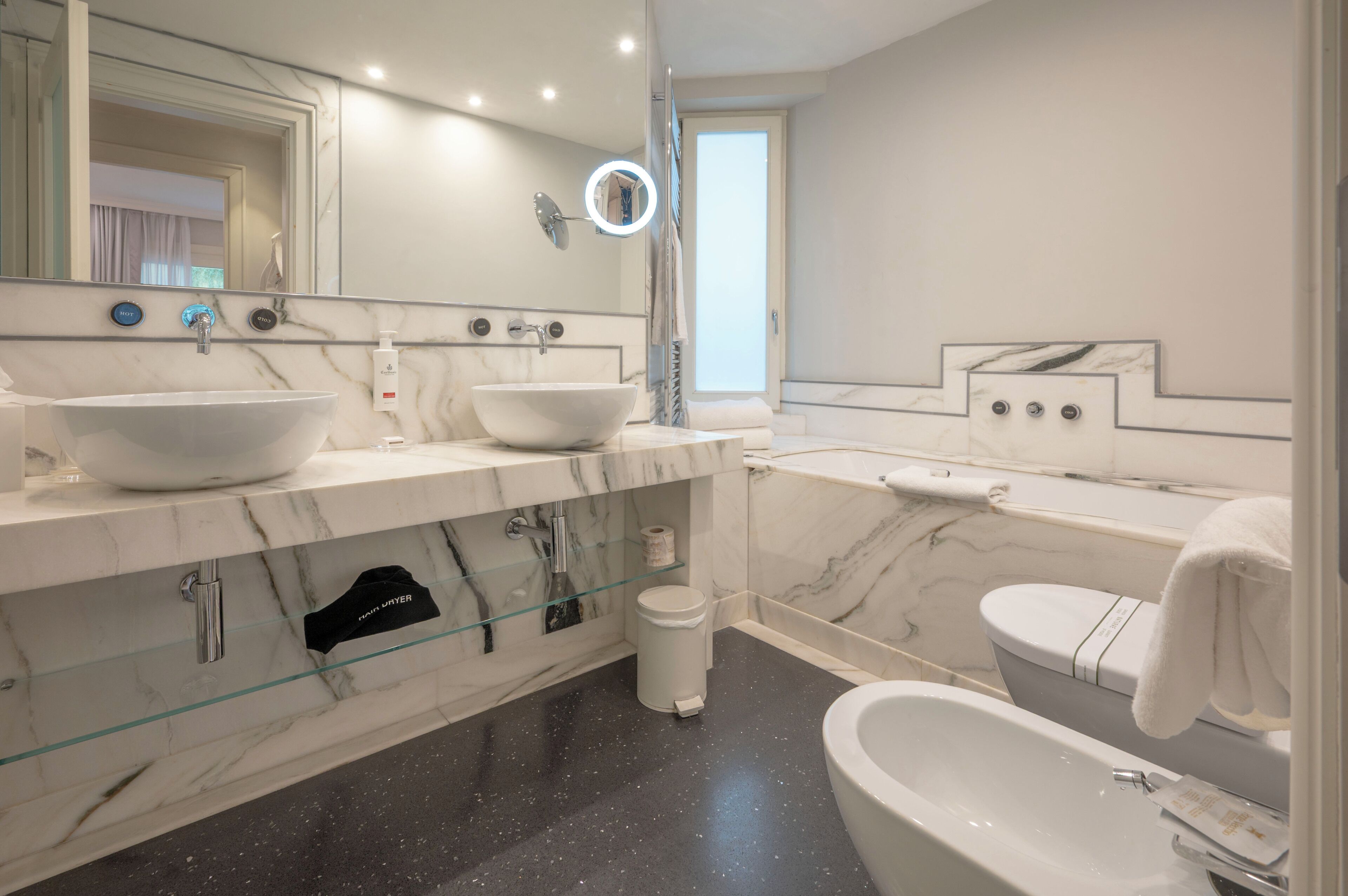 A modern bathroom with two sinks, a bathtub, and a large mirror.