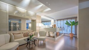 A modern living room with a sofa, armchairs, a coffee table, and a large window with blinds.