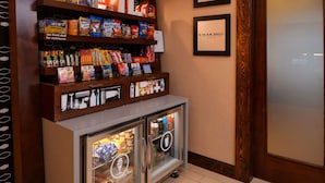 Una barra de aperitivos con estantes llenos de productos y un refrigerador con alimentos.
