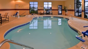 Una piscina interior con agua cristalina, una estación de socorristas y sillas de descanso.