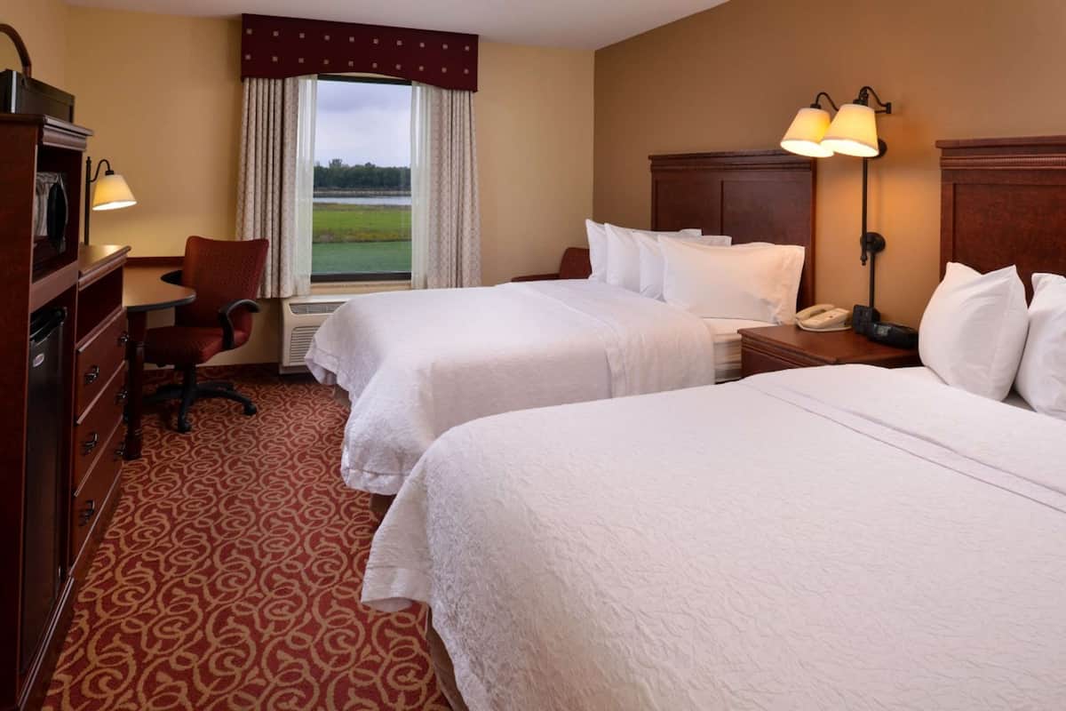 Een hotelkamer met twee bedden, een bureau, een stoel en een dressoir.