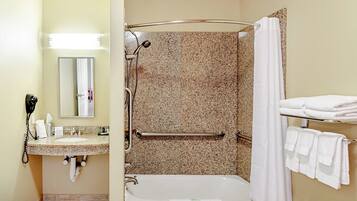 A bathroom with a sink, mirror, shower, and towel rack.