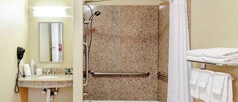 A bathroom with a sink, mirror, shower, and towel rack.
