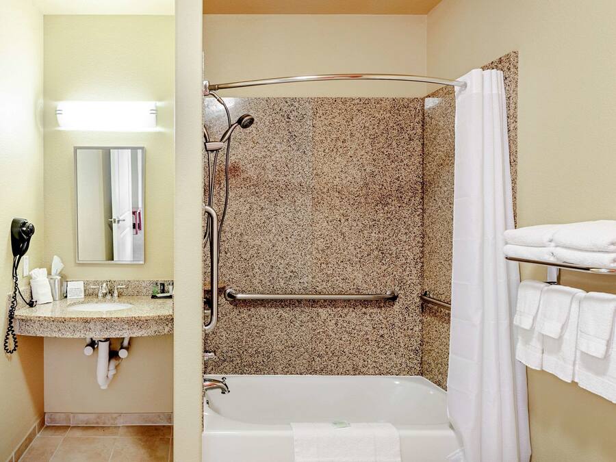 A bathroom with a sink, mirror, shower, and towel rack.