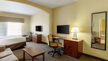 A hotel room with a bed, desk, chair, TV, lamp, and a mirror.